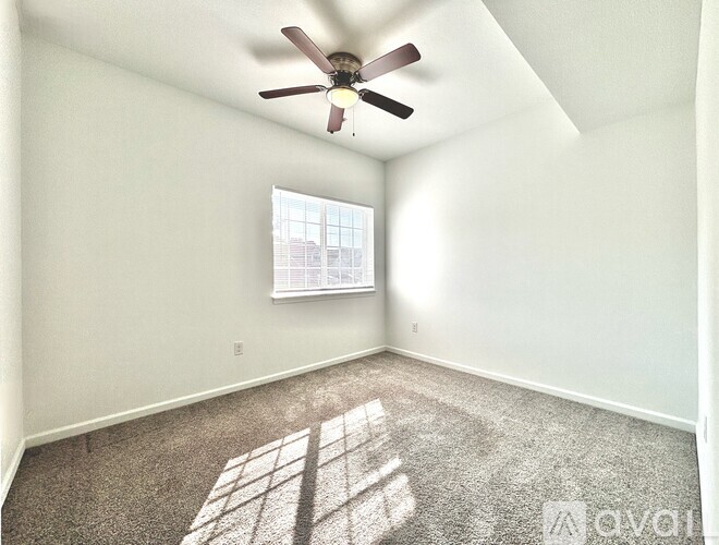 A room with a ceiling fan and a window letting in sunlight.