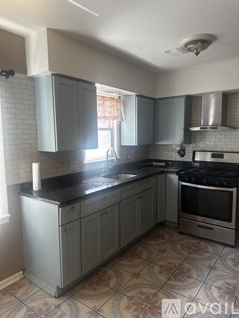 A kitchen with a black countertop and grey cabinets.