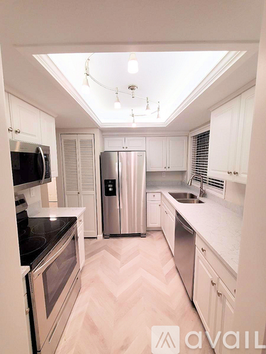 A kitchen with white cabinets and a stainless steel refrigerator.