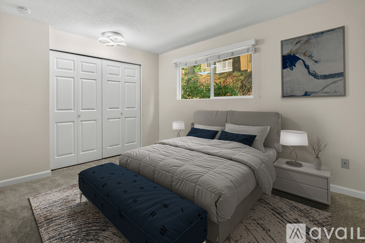 A bedroom with a large bed and a window with a view of greenery outside.