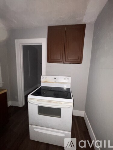 A white oven with a stove top sits in a kitchen with brown cabinets.