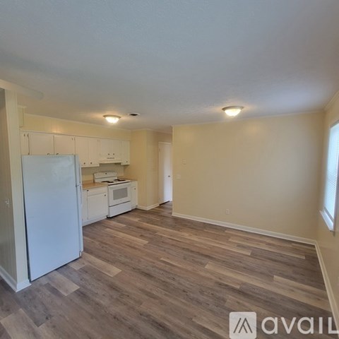 A kitchen with white appliances and wooden floors.