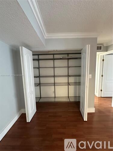 A room with a white ceiling and a wooden floor with a white door open.