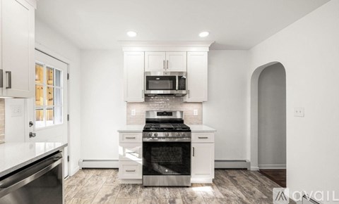 A modern kitchen with white cabinets and stainless steel appliances.