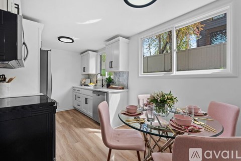 A modern kitchen with a glass table and pink chairs.