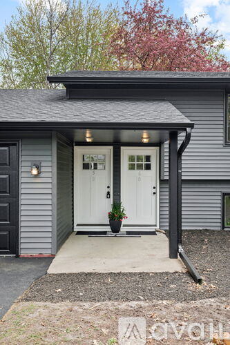 A house with a grey siding and a white door is shown.