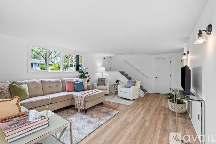 A living room with a sofa, a coffee table, a rug, a TV, and a staircase.