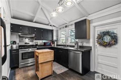 A kitchen with black cabinets and stainless steel appliances.