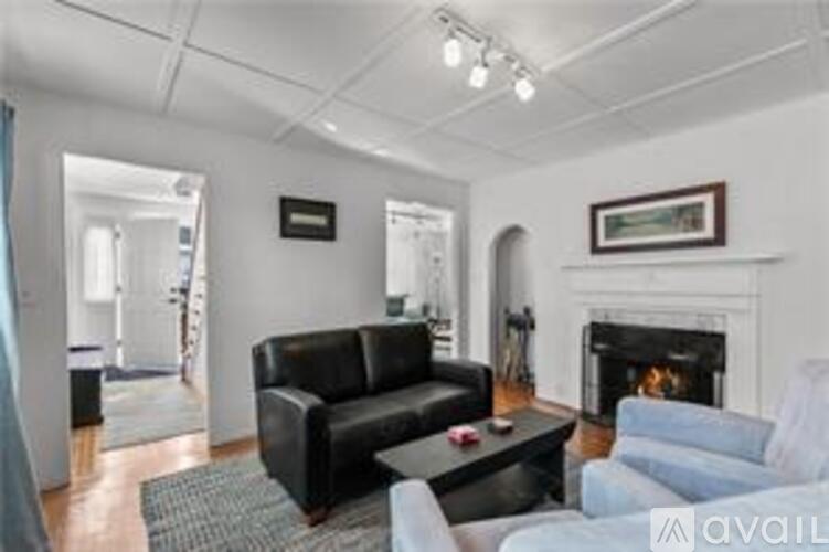 A living room with a black couch, a fireplace, and a painting on the wall.