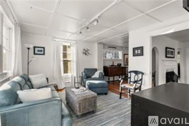 A living room with a blue couch and a grey rug.