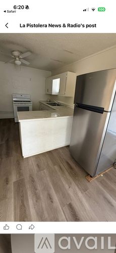 A kitchen with a stainless steel refrigerator and wooden flooring.