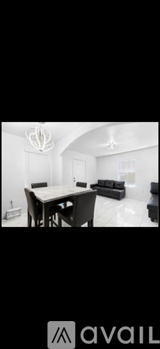 A black and white image of a living room with a dining table and chairs.