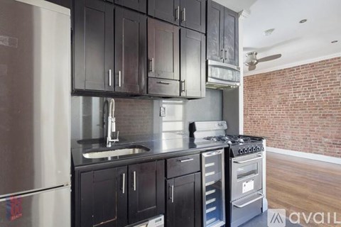 A kitchen with black cabinets and a brick wall in the background.