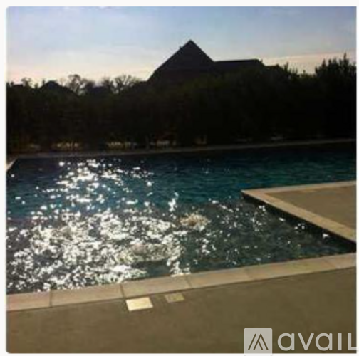A pool with water splashing and a building in the background.
