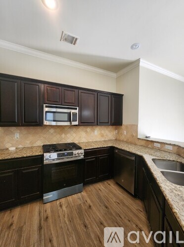 A kitchen with dark wood cabinets and a granite countertop.