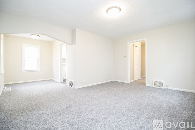 A spacious room with a carpeted floor and a window.