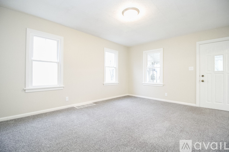 A room with a carpeted floor and three windows.