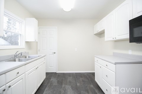 A kitchen with white cabinets and a black microwave.