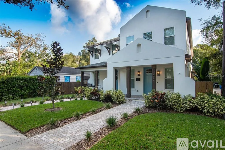 A modern white house with a blue door and a garden in front.
