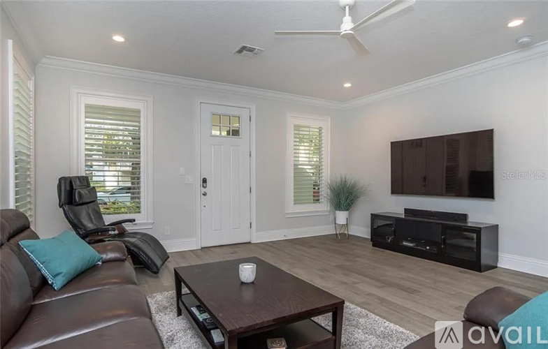 A living room with a brown leather couch, a wooden coffee table, and a flat screen TV mounted on the wall.