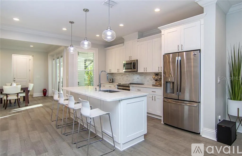 A modern kitchen with white cabinets and stainless steel appliances.