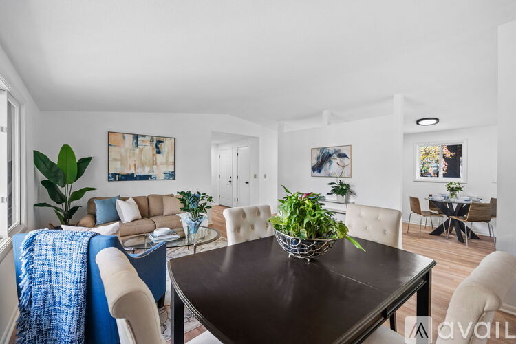 A modern dining room with a dark brown table and white chairs.