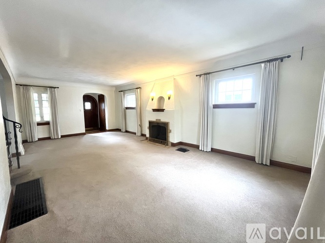 A living room with a fireplace and a window with curtains.