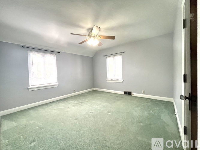 A room with a ceiling fan and two windows.