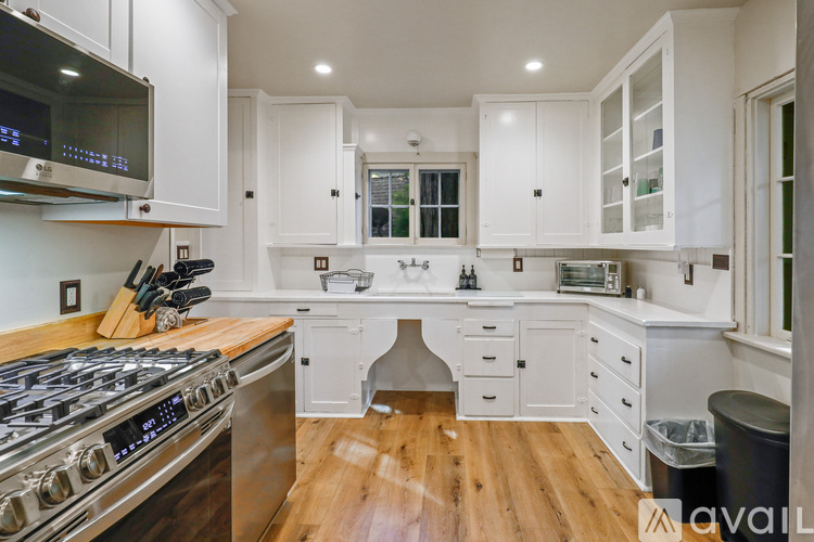 A modern kitchen with white cabinets and a wooden floor.