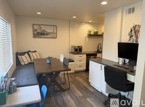 A modern kitchen with a black chair and a wooden table.