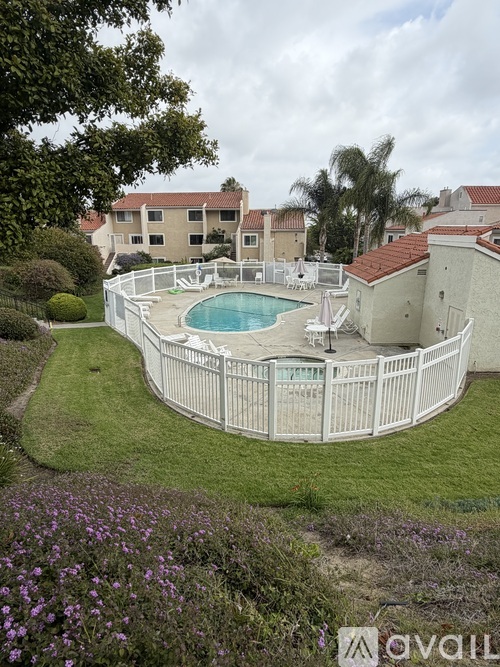 A pool surrounded by a white fence with a building in the background.