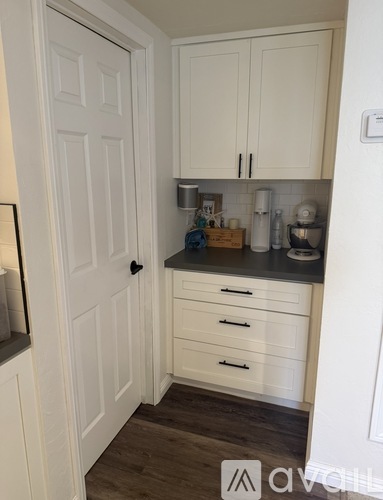 A small kitchen with white cabinets and a white door.