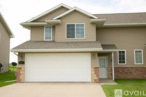 A house with a garage door and a brick pillar.