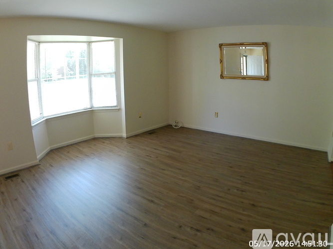 Empty room with wooden floors and a large window.