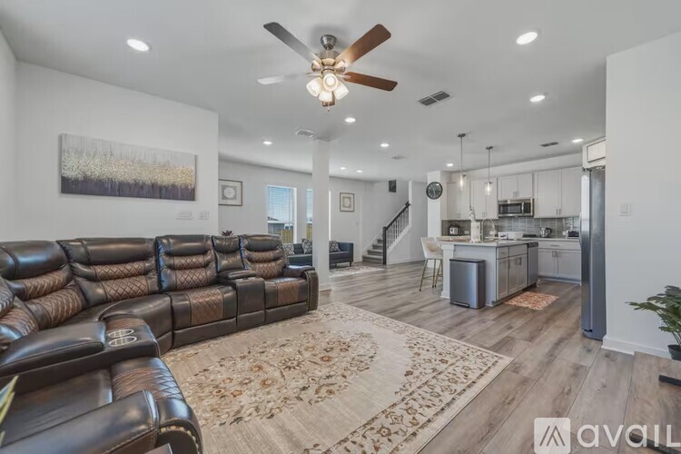 A living room with a brown leather couch and a ceiling fan.