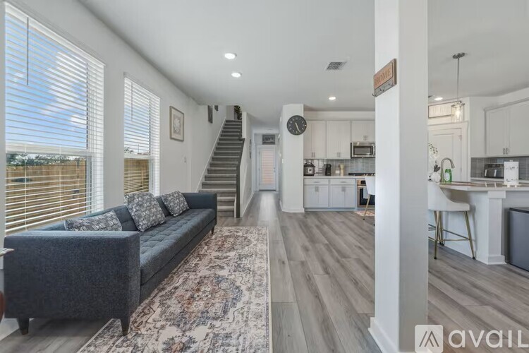 A living room with a grey couch and a rug in front of a staircase.