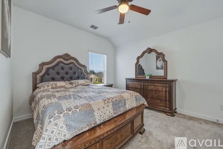 A bedroom with a bed, dresser, and mirror.
