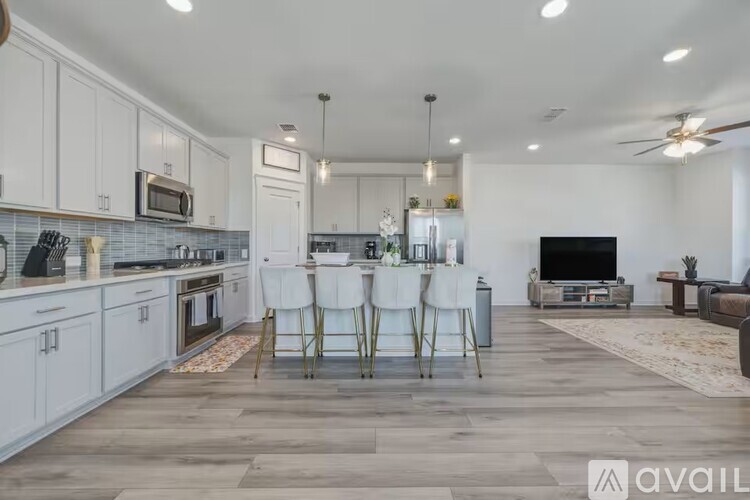 A modern kitchen with white cabinets and a wooden floor.