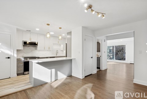 A modern kitchen with white cabinets and a wooden floor.