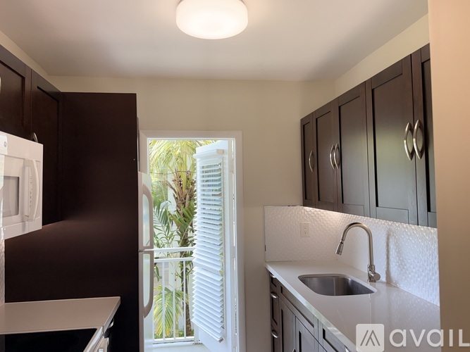 A kitchen with dark brown cabinets and a white sink.
