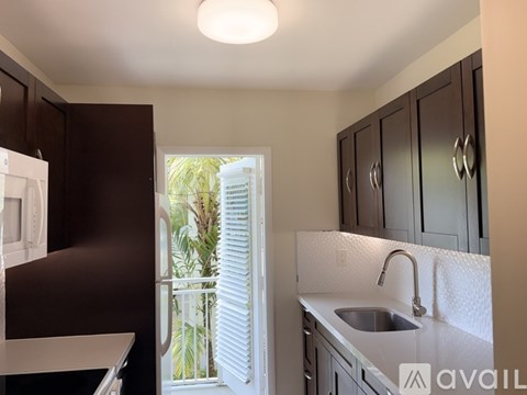 A kitchen with dark brown cabinets and a white sink.