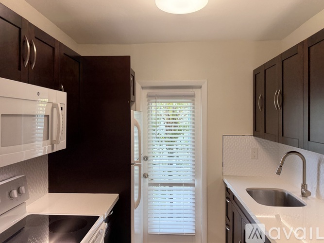A kitchen with dark brown cabinets and white appliances.