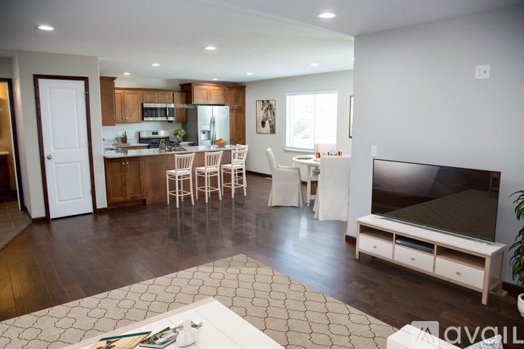 A modern kitchen with white cabinets and a dining area with white chairs.
