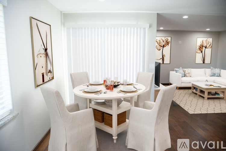 A dining room with a white table and chairs.