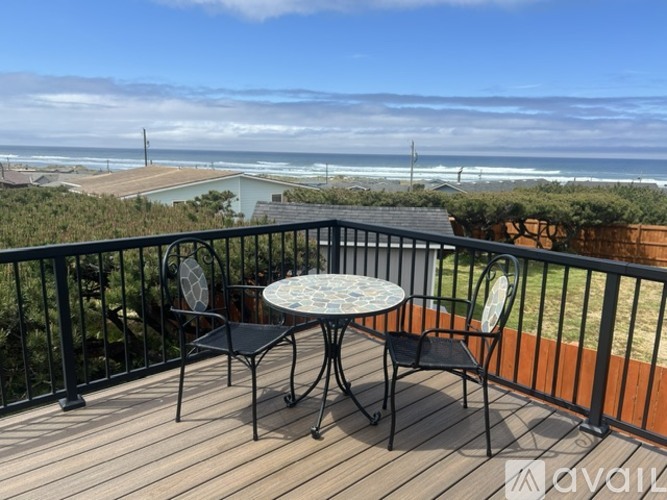A balcony with a table and chairs overlooking the beach.