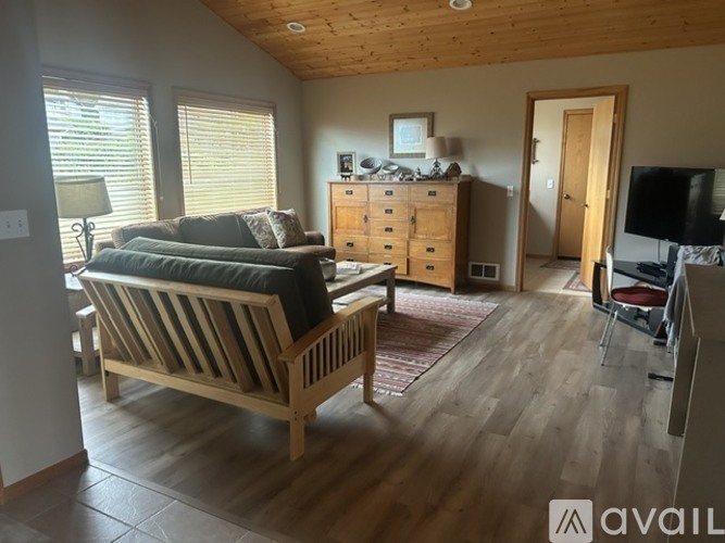 A living room with a sofa, a wooden bench, and a TV.