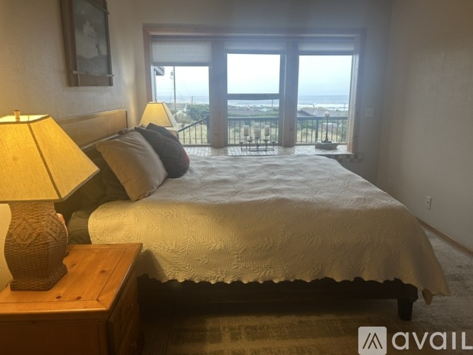 A bedroom with a large bed and a view of the ocean through the windows.