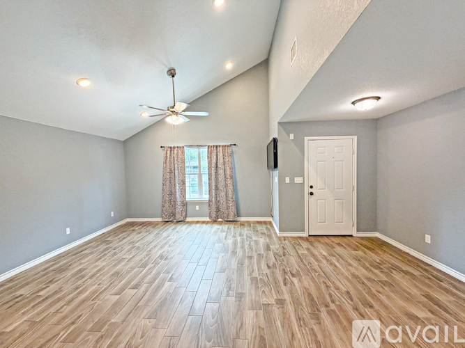 A spacious room with wood flooring and a ceiling fan.