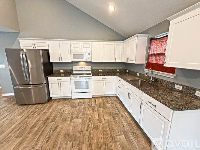 A kitchen with white cabinets and a stainless steel refrigerator.
