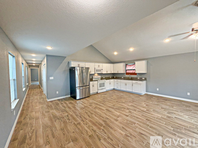 A spacious kitchen with wooden flooring and stainless steel appliances.